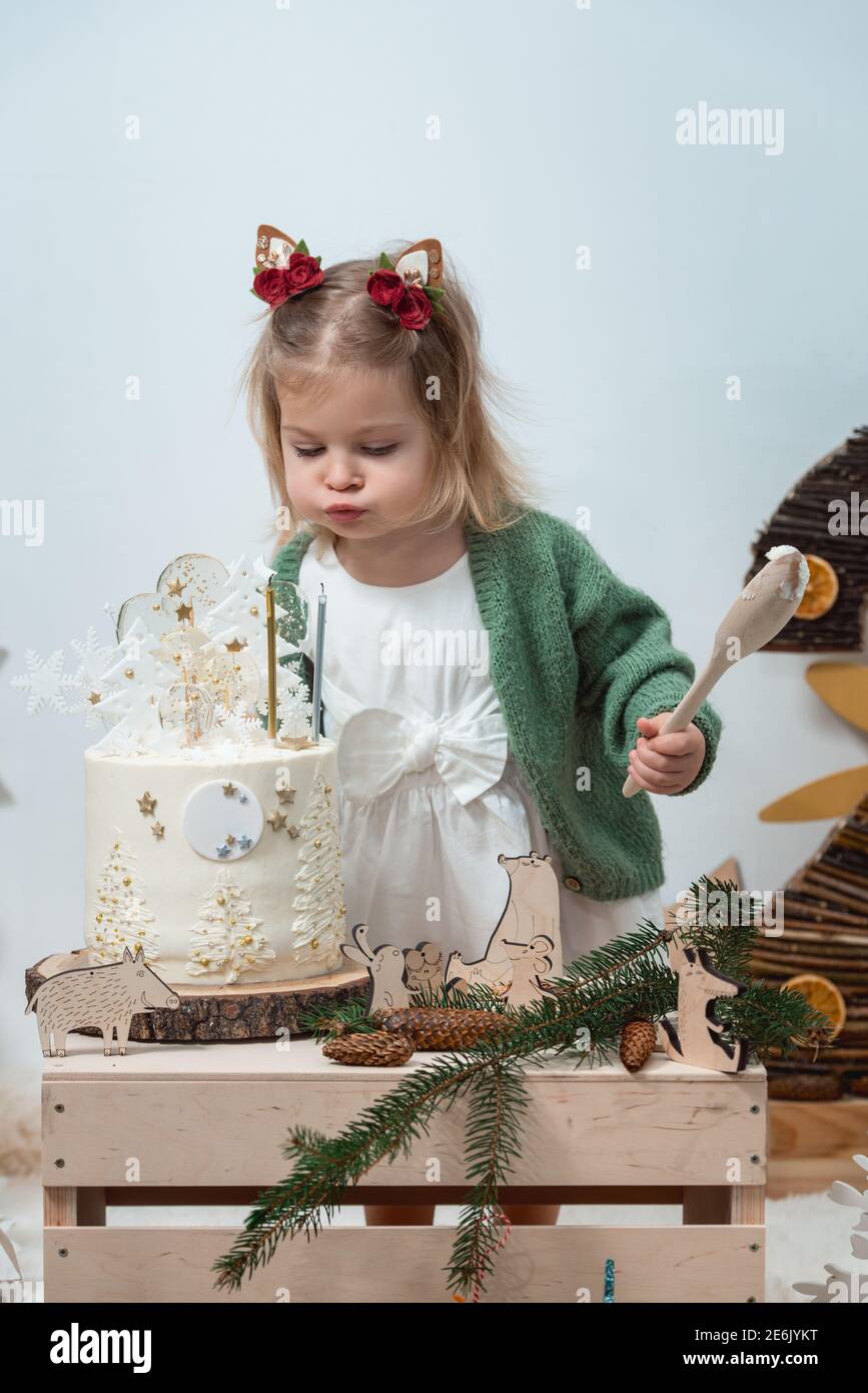 Decoración de cumpleaños para niños. 2 años. Una chica linda en un cárdigan  verde cerca de una torta blanca de cumpleaños Fotografía de stock - Alamy