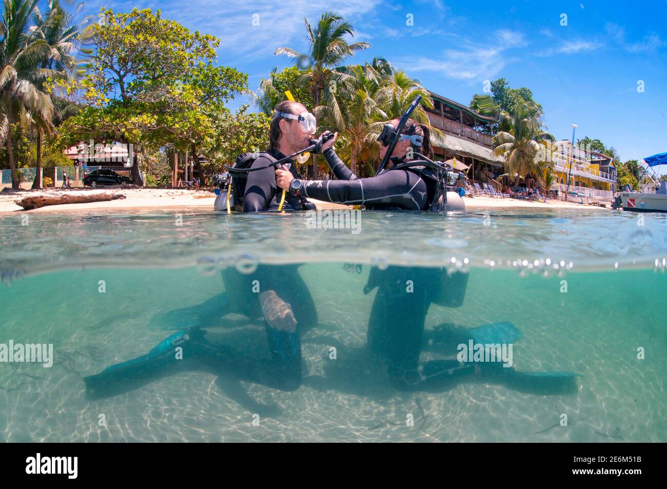 Instructor de buceo con estudiante durante la clase de enseñanza de buceo en la playa medio cuerpo en el agua. West End, Roatán, Islas de la Bahía, Honduras Foto de stock
