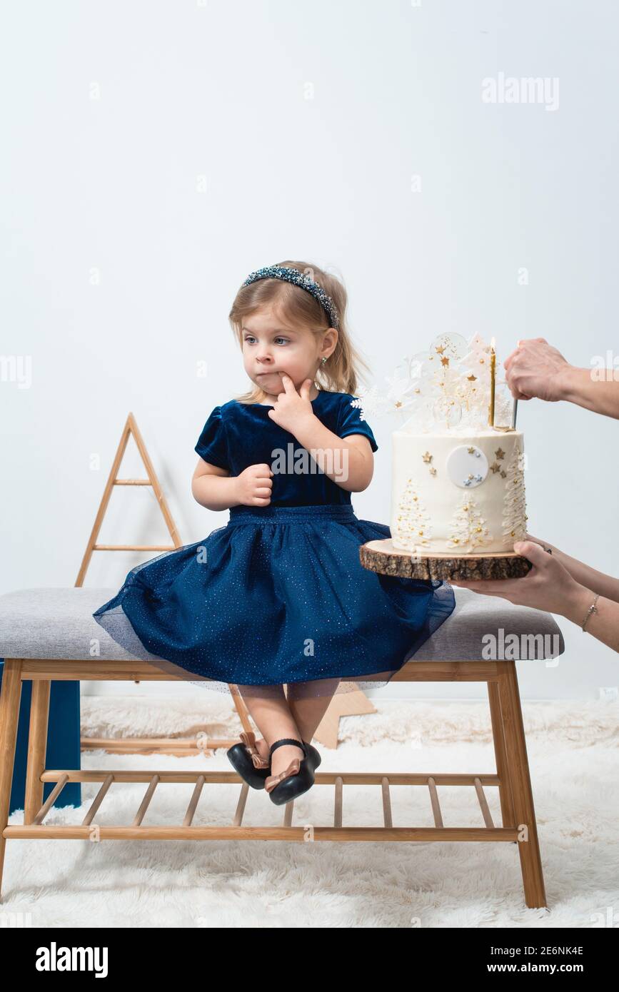 Decoración de cumpleaños para niños. Linda niña en un vestido azul cerca de blanco pastel de cumpleaños Fotografía de stock - Alamy