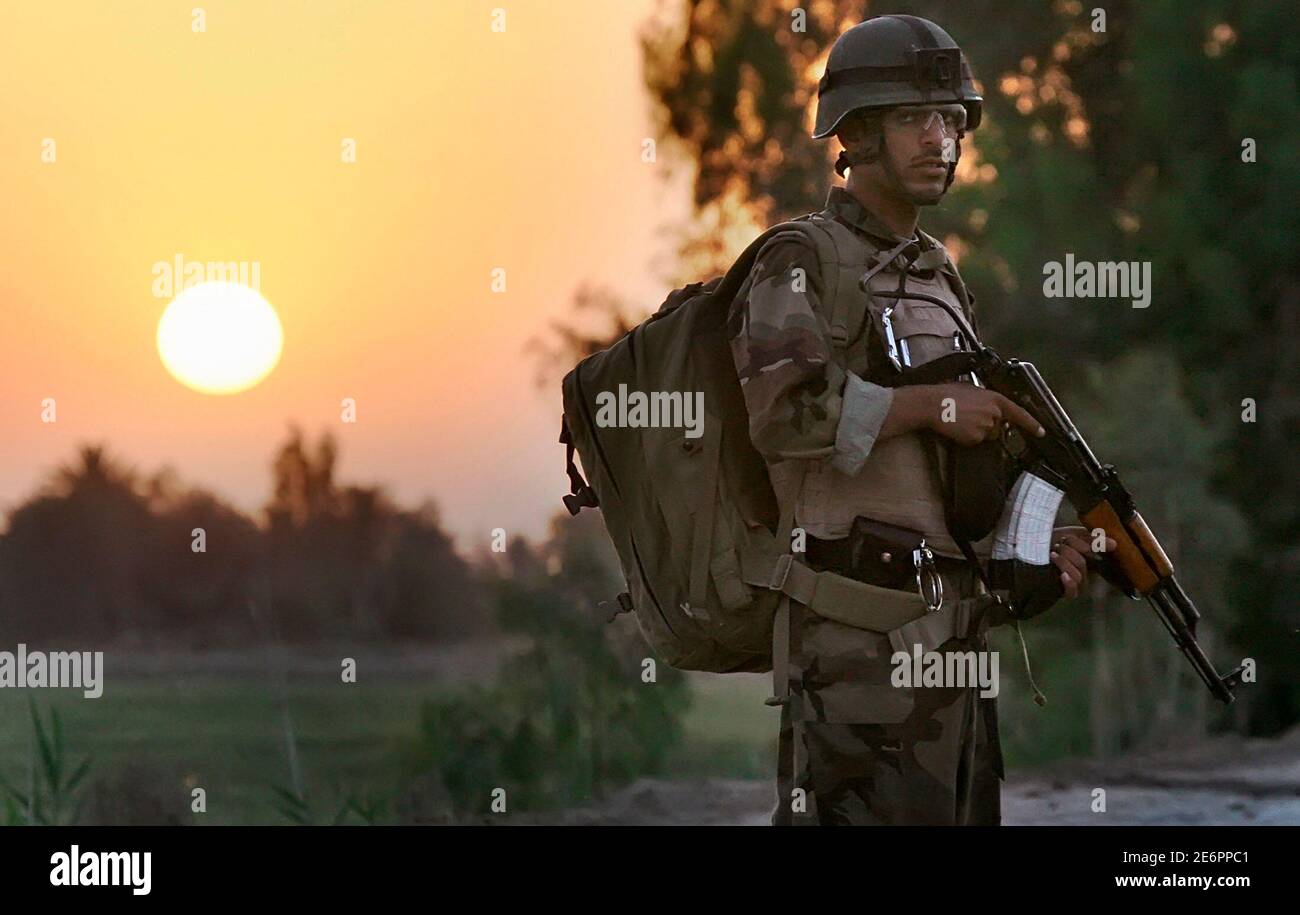 The sun rises as an Iraqi soldier prepares to take part in a joint operation with U.S. army troops near Mahmudiya, south of Baghdad April 16, 2007. REUTERS/Bob Strong (IRAQ) Foto de stock