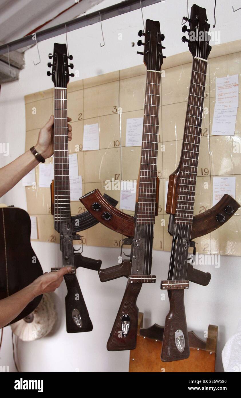 Un fabricante de instrumentos exhibe tres guitarras eléctricas, que fueron  convertidas de rifles AK47, en Bogotá el 13 de septiembre de 2006. El  palisandro pulido y el toque de deft de un