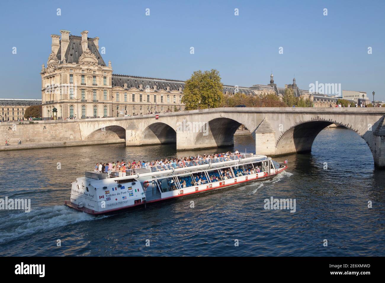 Barco en el Sena en el fondo el Musee de Louvre y el puente Pont Royal Foto de stock