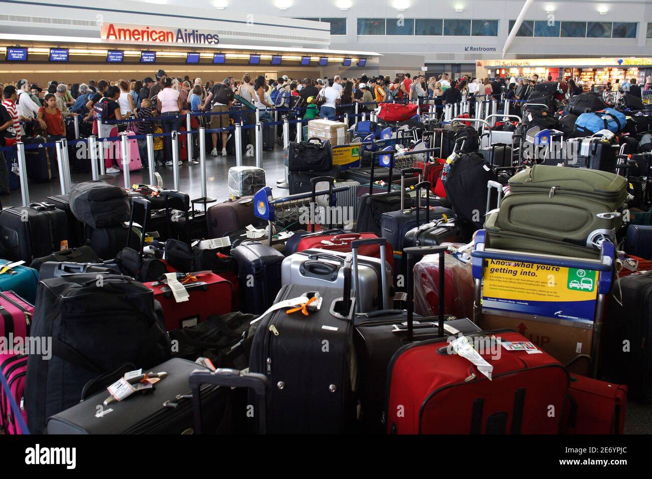 A luggage pile is seen in the foreground as customers wait in line after a  computer glitch crippled the baggage handling system at the American  Airlines' Terminal 8 at New York's John