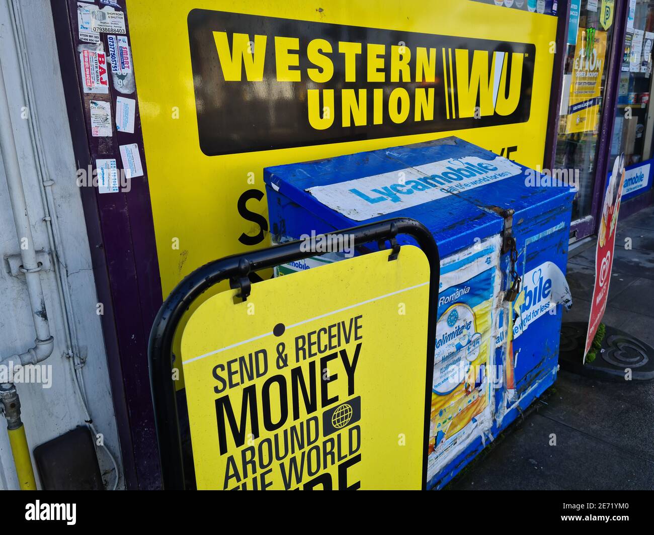 Los carteles publicitarios para Western Union fuera de una tienda de la esquina. Una empresa financiera estadounidense que ofrece un servicio de transferencia de dinero a nivel mundial. Foto de stock