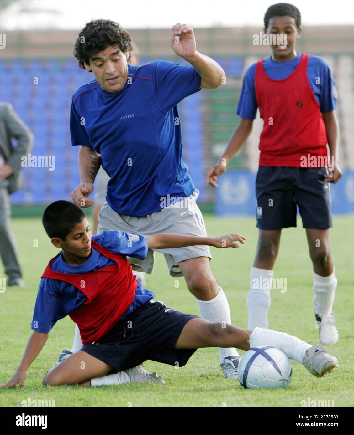 Argentina soccer legend Diego Maradona (C) challenges Qatar's under-14  player while playing for the ASPIRE team in Doha November 17, 2005.  Maradona and Brazil's Pele were headlining the guest list for the