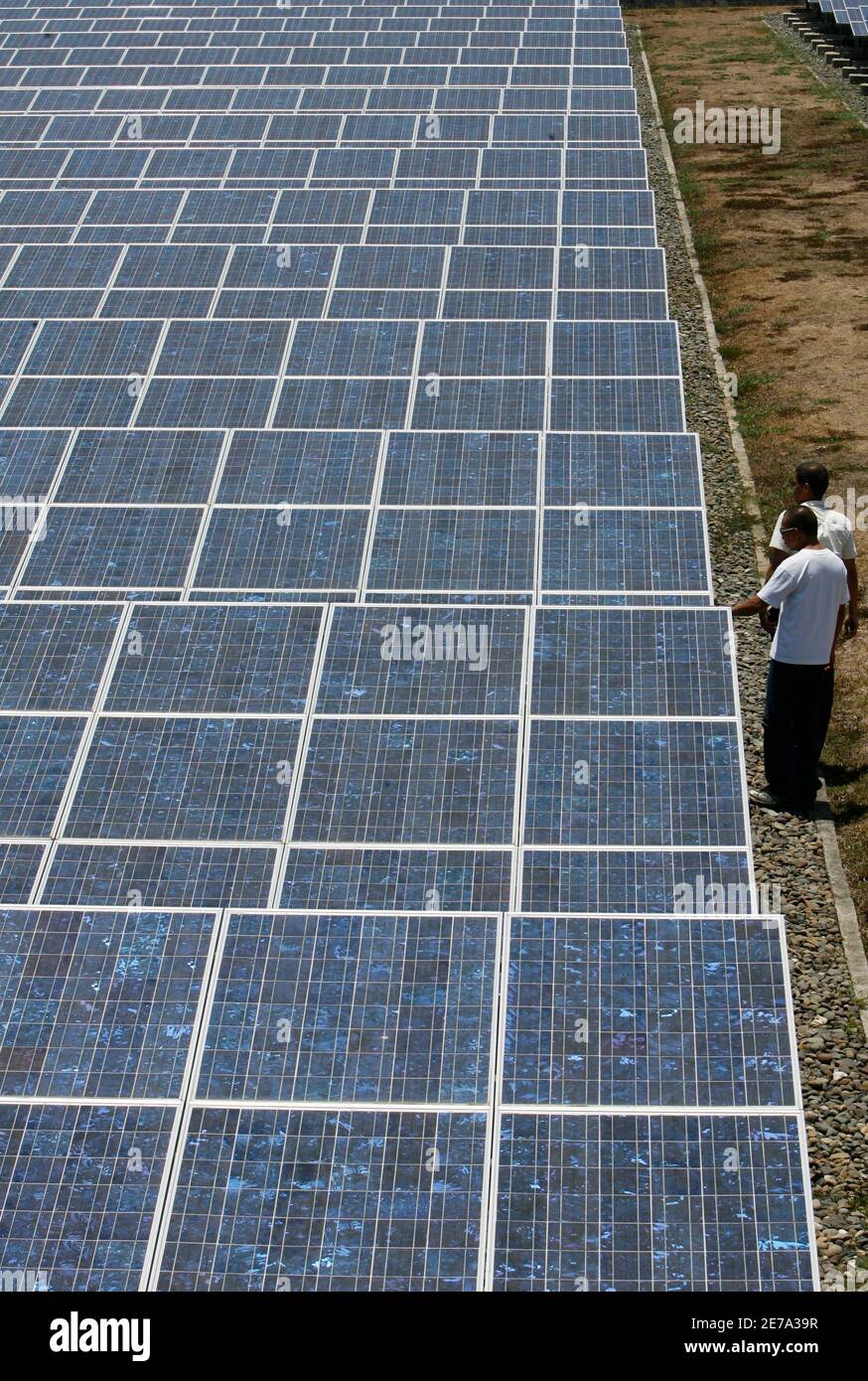 Trabajadores de Cagayan Electric Power and Light Co. Inc (CEPALCO),  inspecciona una serie de paneles solares de dos hectáreas instalados en la  aldea de Indahag en Cagayan de Oro, al sur de