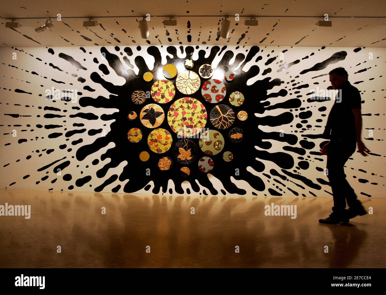 An installation worker passes a mixed media artwork called "Black Gold