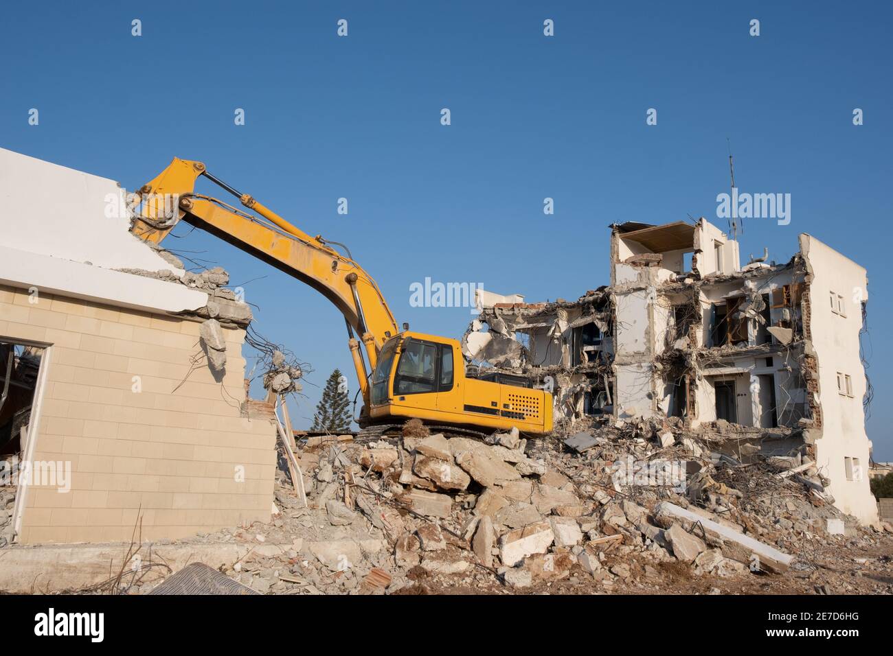 Excavadora oruga trabajando para la demolición de un hotel antiguo. Excavadora en el lado de la construcción. Foto de stock