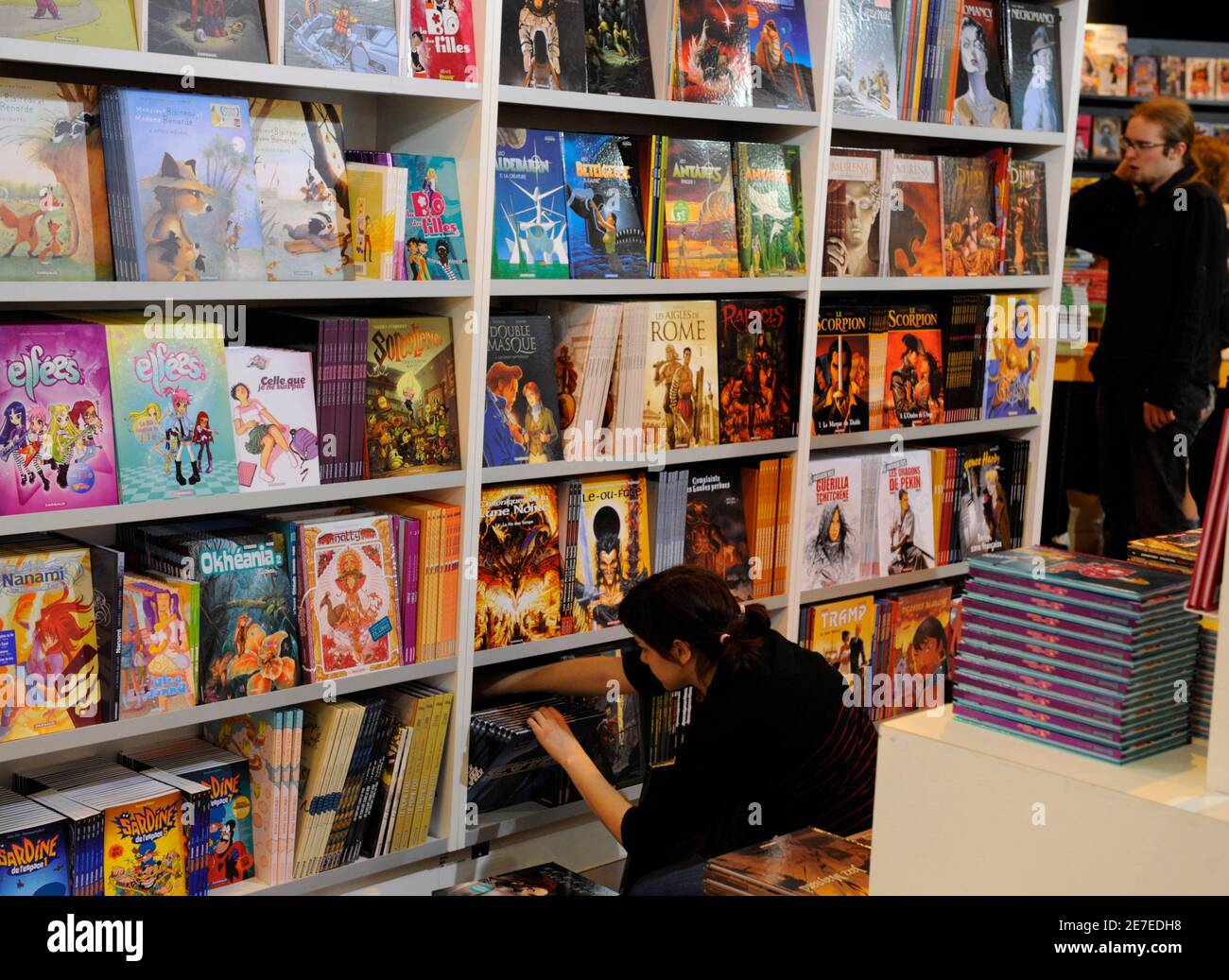 Un empleado organiza libros de dibujos animados en un estante de libros durante la instalación de la Feria anual del Libro de París 12 de marzo de 2009. La Feria anual del Libro de París, con México como invitado especial, tiene lugar del 13 al 18 de marzo. REUTERS/Philippe Wojazer (FRANCIA ENTRETENIMIENTO) Foto de stock