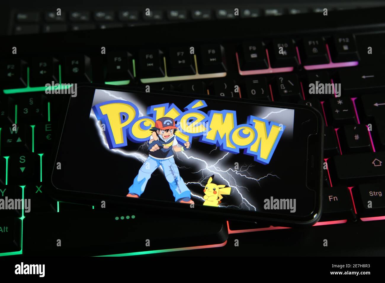 Viersen, Alemania - 9 de enero. 2021: Primer plano de la pantalla del  smartphone con el logotipo de la inscripción de juego en línea pokemon en  el teclado de ordenador iluminado Fotografía