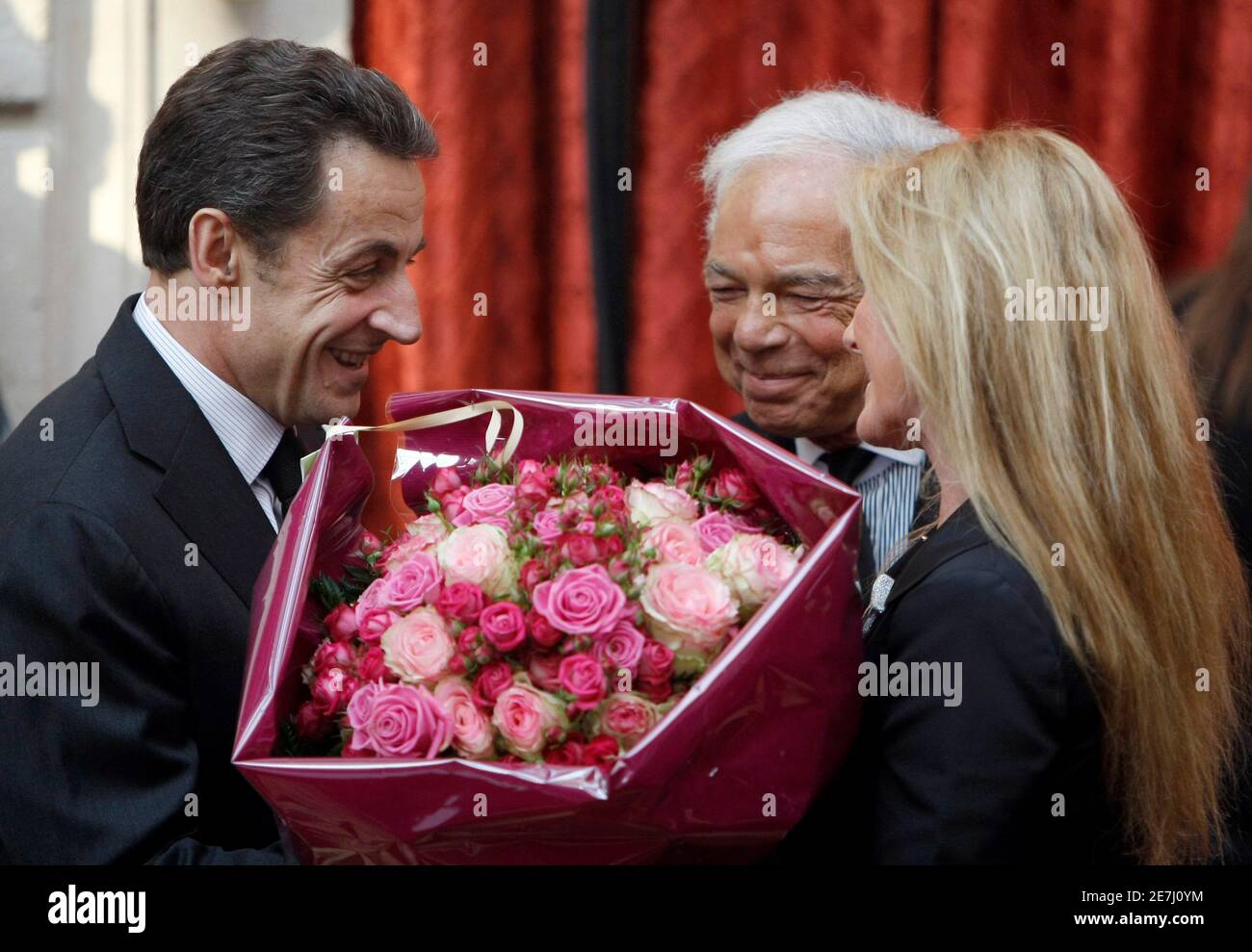 El presidente de Francia, Nicolas Sarkozy (L), ofrece un ramo de rosas a  Ricky, esposa del diseñador de moda estadounidense Ralph Lauren (C) quien  fue nombrado Chevalier de la Legión de honor,