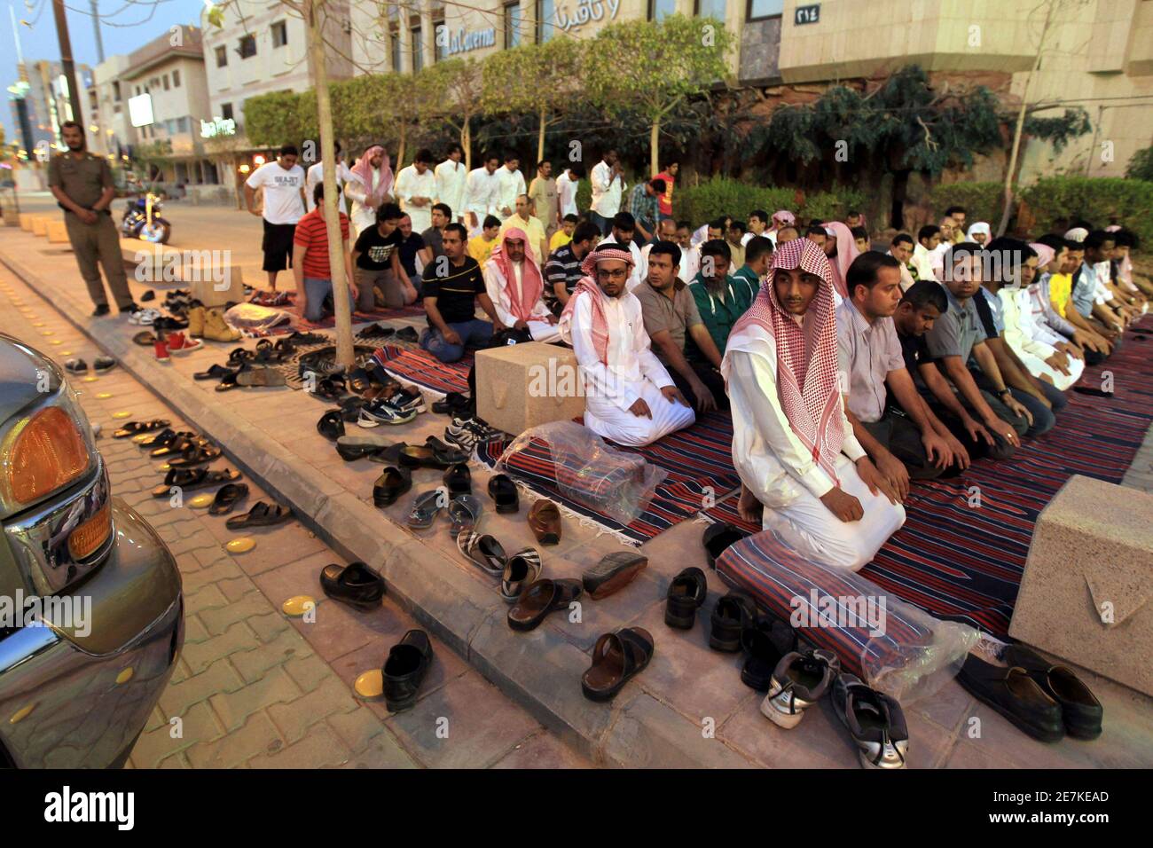 Members of the Committee for the Promotion of Virtue and Prevention of Vice, or religious police, perform dusk prayers with Saudi youth on the street outside coffee shops in Riyadh June 27, 2010. The men conducted the prayers during half-time of the World Cup soccer match between Germany and England, which they had been watching. The police have been ensuring that people watching World Cup soccer matches at the coffee shops continue to conduct their prayers during the duration of the soccer tournament. REUTERS/Fahad Shadeed (SAUDI ARABIA - Tags: SPORT SOCCER WORLD CUP RELIGION IMAGES OF THE DA Foto de stock