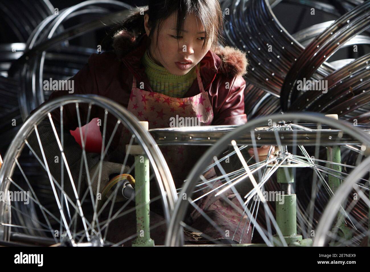 Un trabajador chino pone ruedas de bicicleta en la fábrica de bicicletas  'Forever' en Shanghai 22 de diciembre de 2005. China exporta ahora 50  millones de los 75 millones de bicicletas que