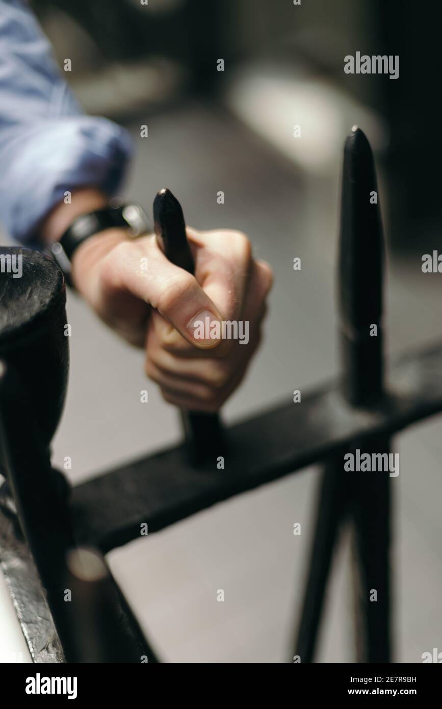 La mano de un hombre agarrando una valla de hierro Fotografía de stock -  Alamy