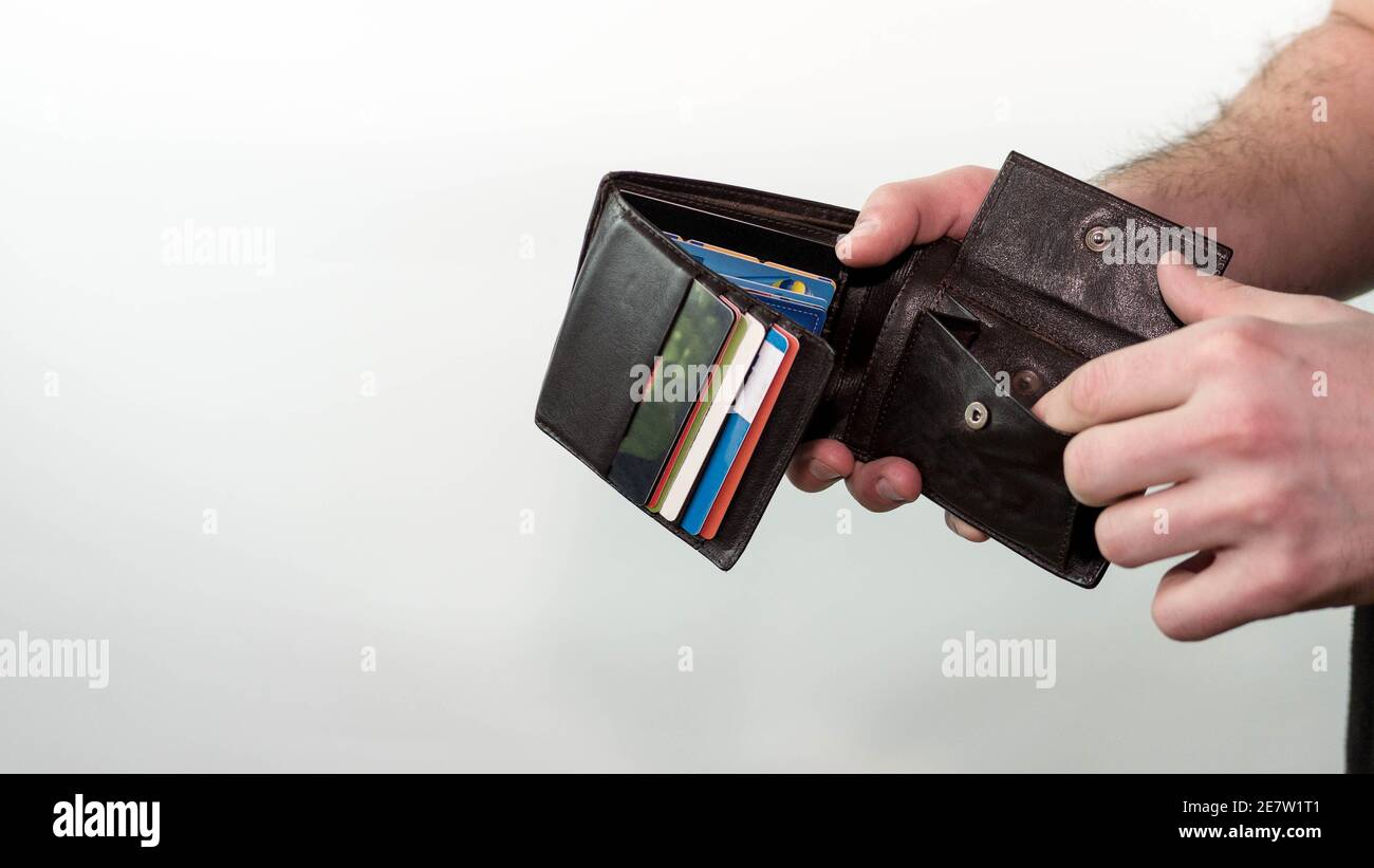 Un hombre mira en una cartera vacía sin dinero, una cartera con tarjetas de  crédito. Sobre fondo blanco Fotografía de stock - Alamy
