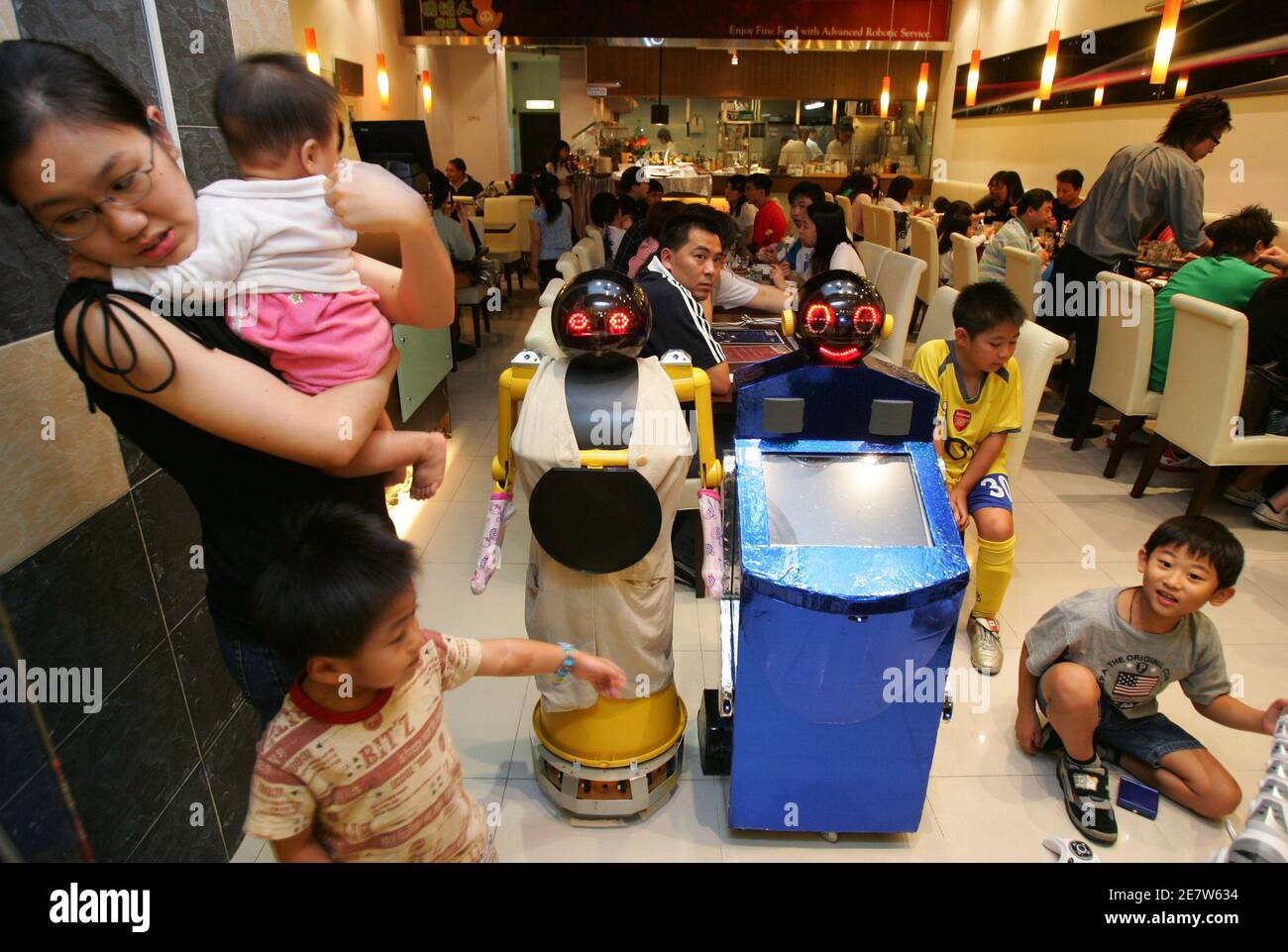 Children play with Robot No.1 (R) and No.2 at a restaurant called Robot  Kitchen in Hong Kong October 14, 2006. Robot No.1 is designed to take  orders from customers while Robot No.2