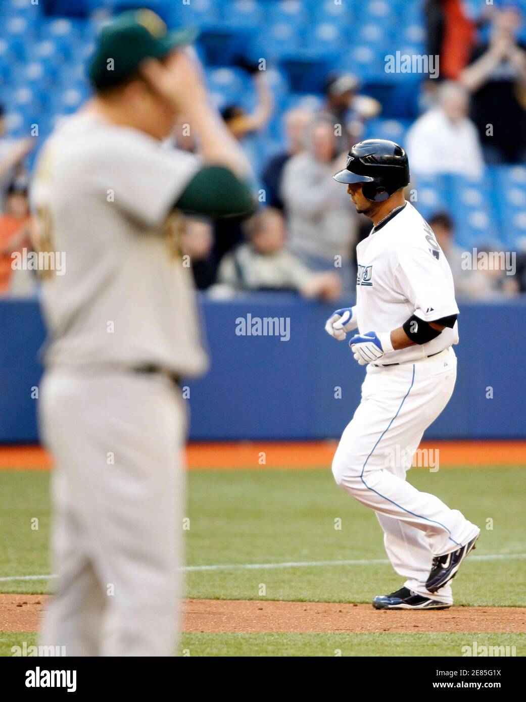 Toronto Blue Jays batter Alex Gonzalez (R) runs behind Oakland Athletics  pitcher Trevor Cahill after hitting a three-run home run during the second  inning of their MLB American League baseball game in