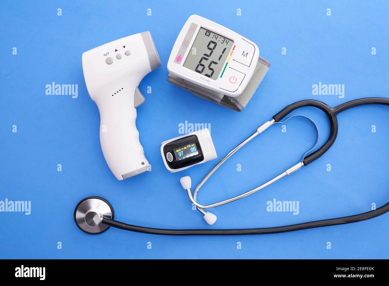 Un monitor de presión arterial, oxímetro, termómetro digital y estetoscopio  sobre fondo azul Fotografía de stock - Alamy