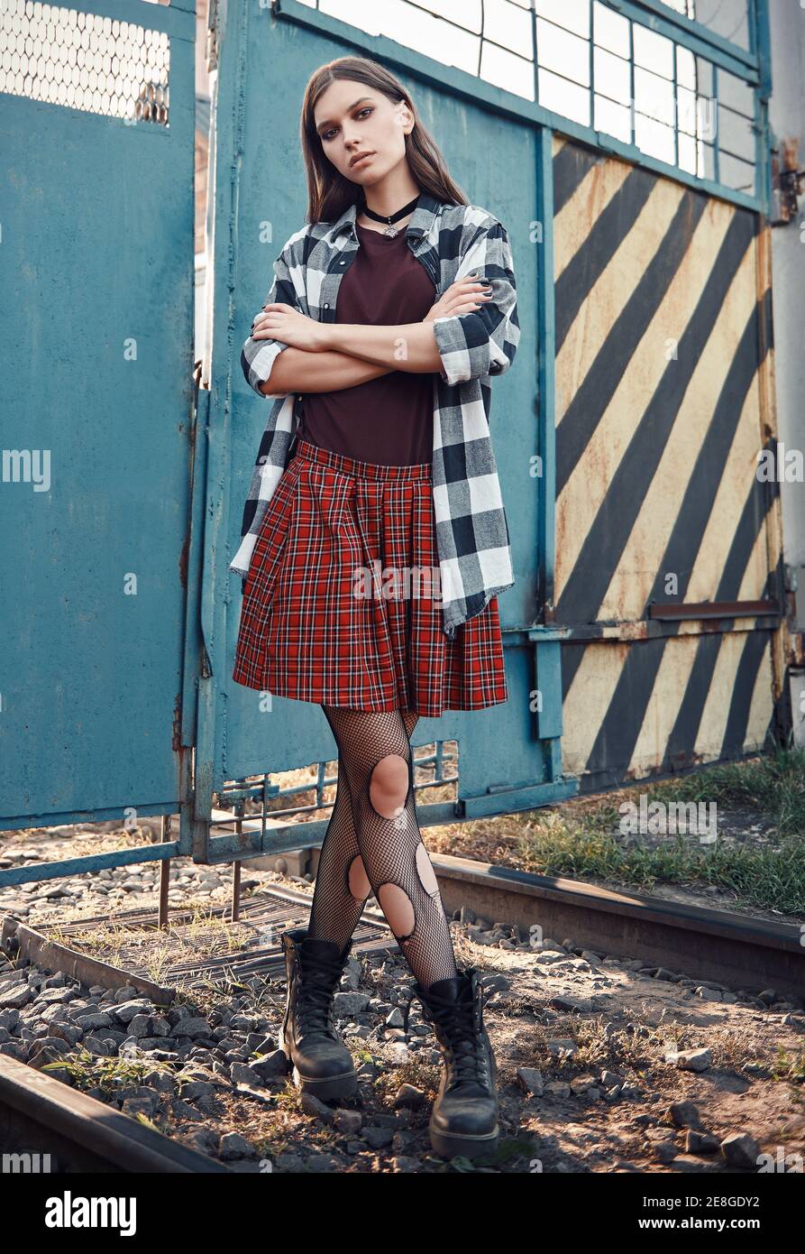 Retrato al aire libre de la hermosa chica grunge (roca) en lugar  industrial. Modelo informal vestido con falda a cuadros y camisa, botas y  medias holey Fotografía de stock - Alamy