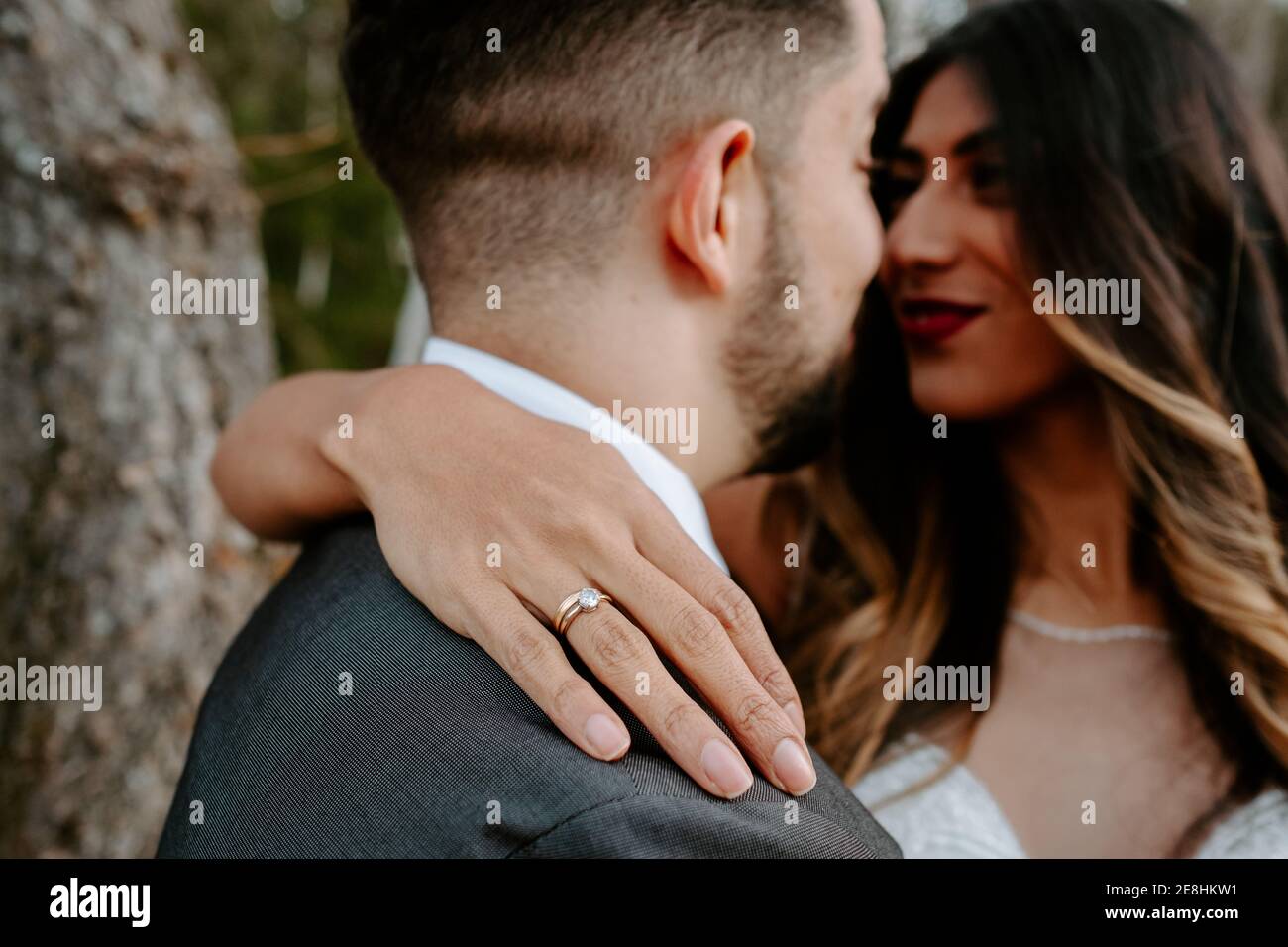 joven novio en traje elegante abrazando frente de novia agraciada vestido  blanco mientras está de pie en el bosque de otoño en la boda día Fotografía  de stock - Alamy