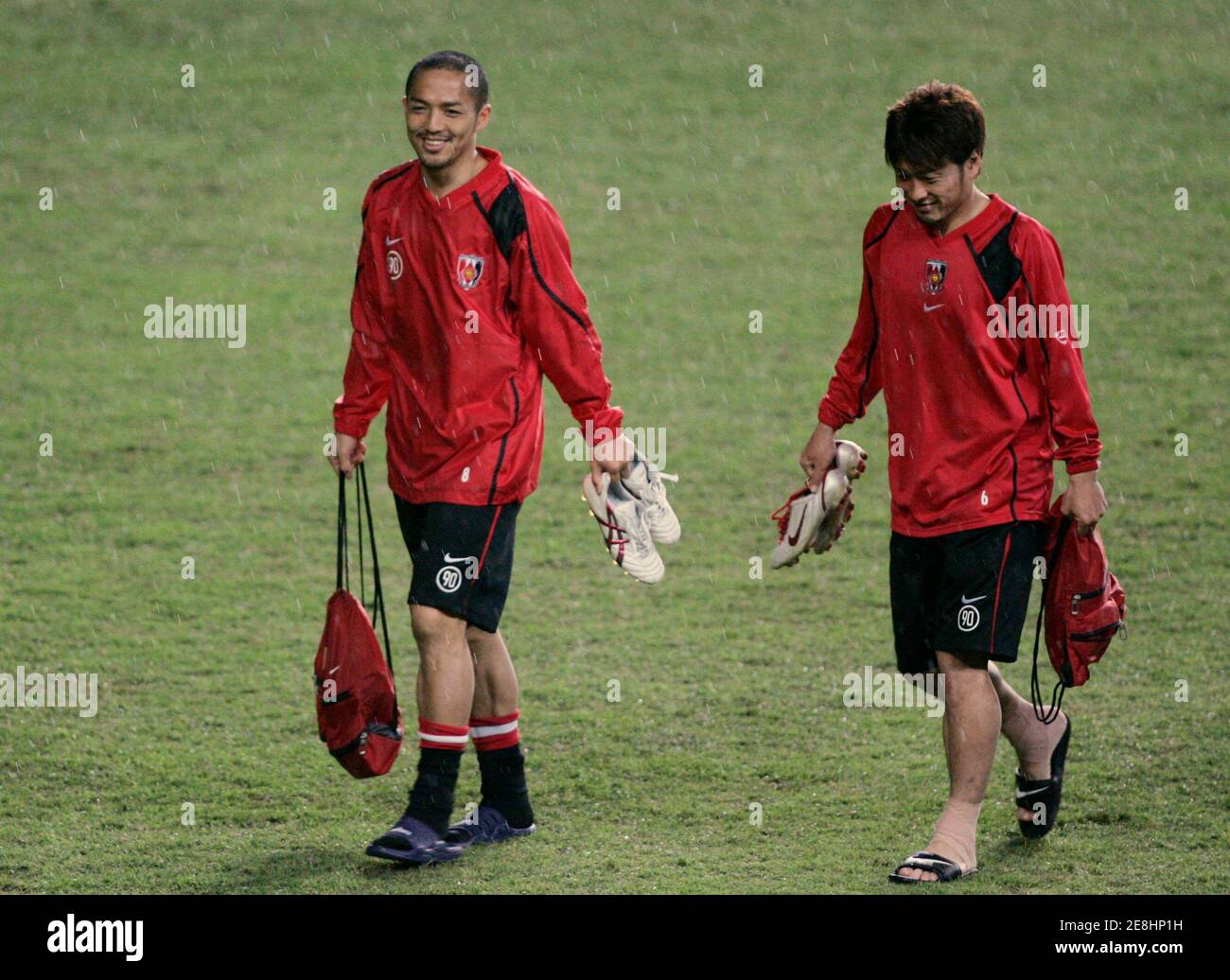 Shinji Ono (L) y la compañera de equipo Nobuhisa Yamada de los diamantes rojos de Urawa de Japón caminan bajo la lluvia durante el entrenamiento en el estadio de fútbol de Sydney 20 de marzo de 2007. Los diamantes rojos de Urawa jugarán contra el Sydney FC en el partido de fútbol de la Liga de Campeones de la Confederación Asiática de Fútbol (AFC) el 21 de marzo. REUTERS/will Burgess (AUSTRALIA) Foto de stock