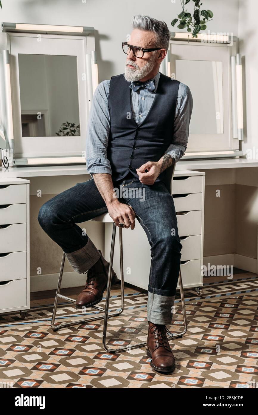 Moderno hombre de negocios hipster maduro en gafas y ropa de moda de  aspecto fuera en silla en casa Fotografía de stock - Alamy