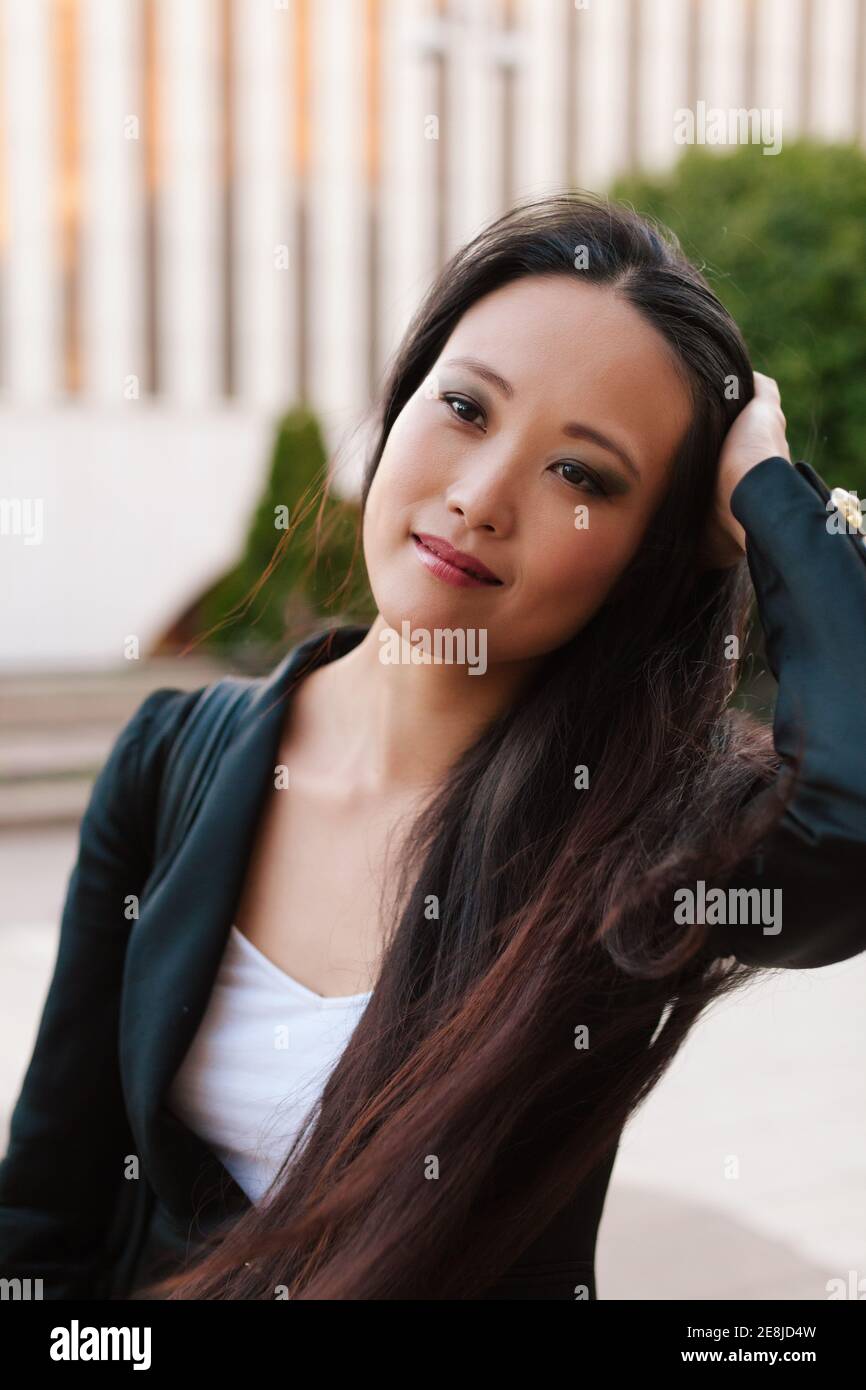Mujer empresaria étnica encantada con ropa informal elegante de pie la  calle y mirando fuera de día Fotografía de stock - Alamy