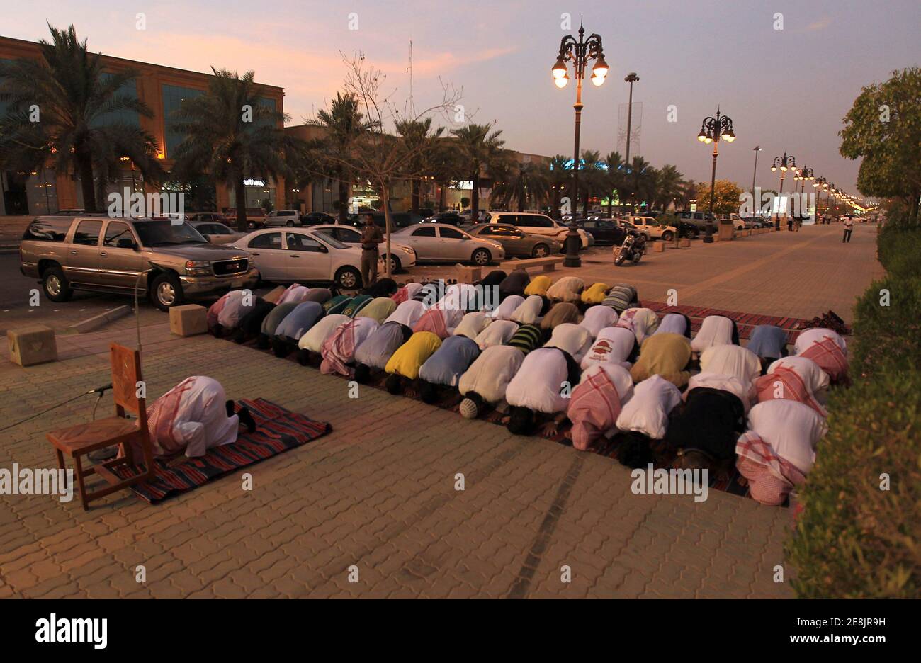 Members of the Committee for the Promotion of Virtue and Prevention of Vice, or religious police, perform dusk prayers with Saudi youth on the street outside coffee shops in Riyadh June 27, 2010. The men conducted the prayers during half-time of the World Cup soccer match between Germany and England, which they had been watching. The police have been ensuring that people watching World Cup soccer matches at the coffee shops continue to conduct their prayers during the duration of the soccer tournament. REUTERS/Fahad Shadeed (SAUDI ARABIA - Tags: SPORT SOCCER WORLD CUP RELIGION) Foto de stock
