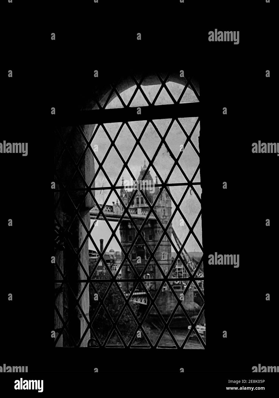 Una captura vertical en escala de grises de una ventana antigua con el vista de un edificio histórico en el fondo Foto de stock