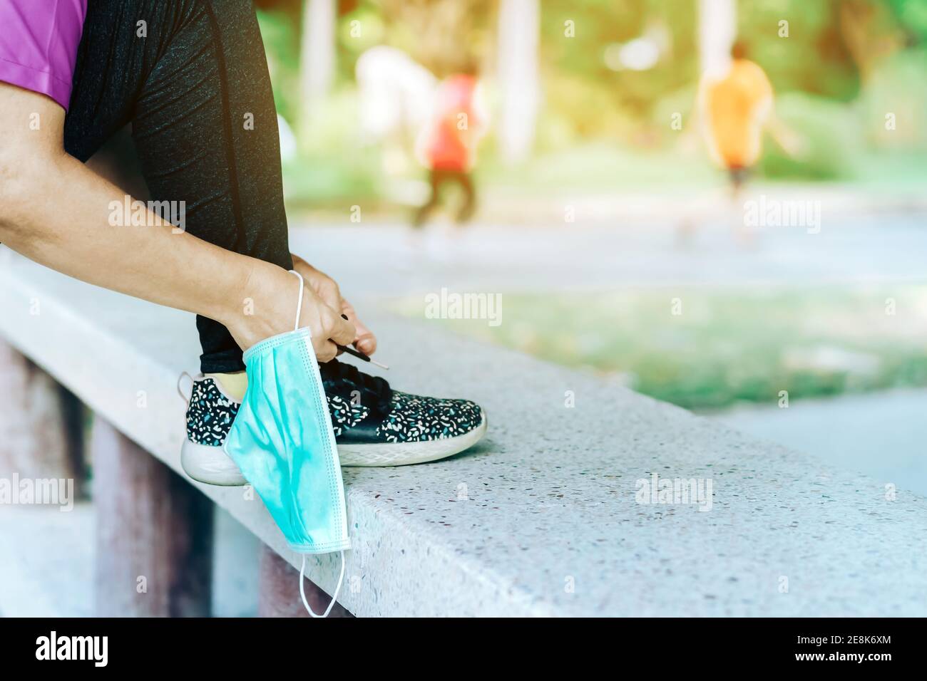 Mujer de fitness sacar su máscara quirúrgica preparándose para hacer  ejercicio lazando zapatos de running para correr al aire libre. Nuevo  estilo de vida normal. Atención de salud Fotografía de stock -