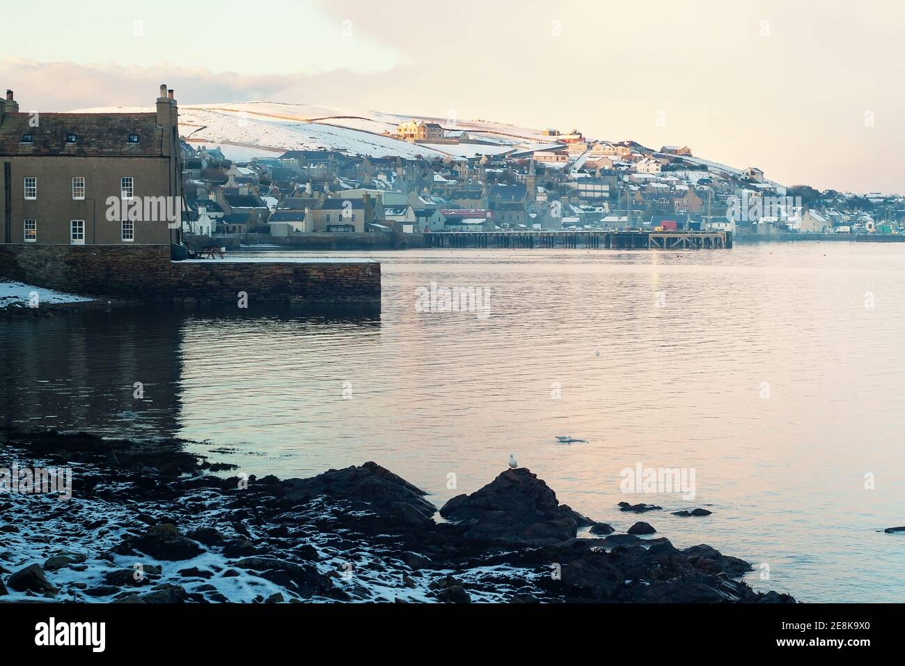 Vista frente al mar de la ciudad de pescadores Stromness en el norte de Escocia Islas Orkney con casas tradicionales construidas en piedra y muelles privados en la niebla de invierno Foto de stock