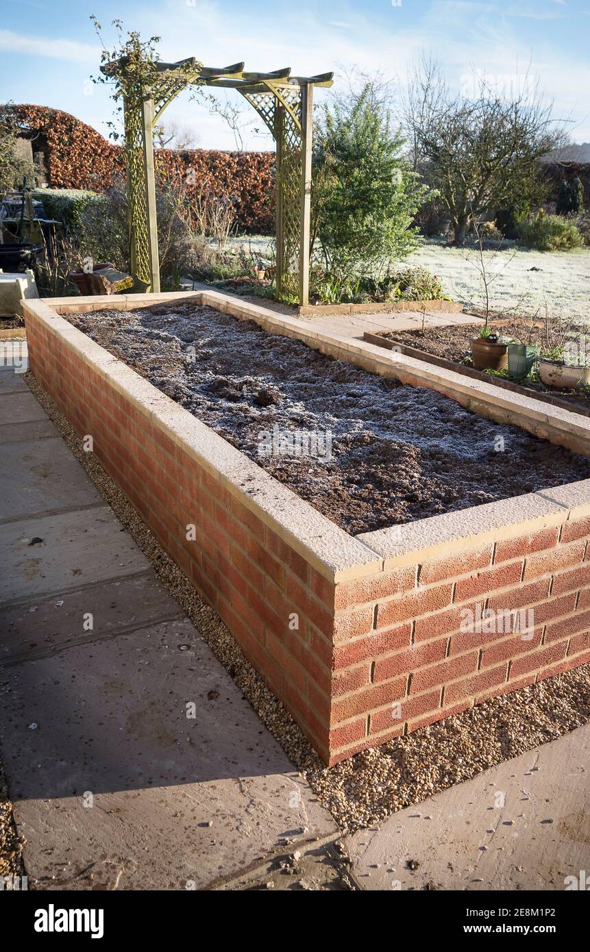 Una plantadora de ladrillo construido recientemente en un jardín inglés para facilitar la jardinería para los pensionistas a atender Foto de stock