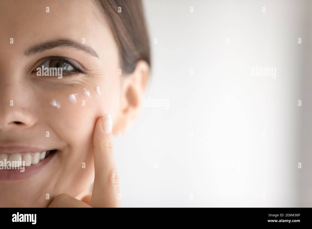Retrato de mujer sonriente aplique crema en la piel de la cara Foto de stock