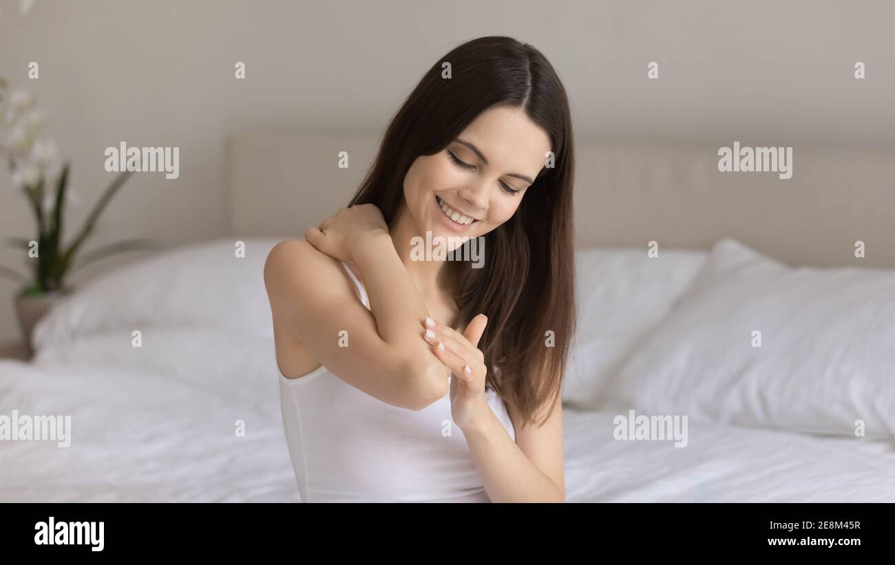 Mujer joven sonriente aplique crema en la piel de la mano Foto de stock