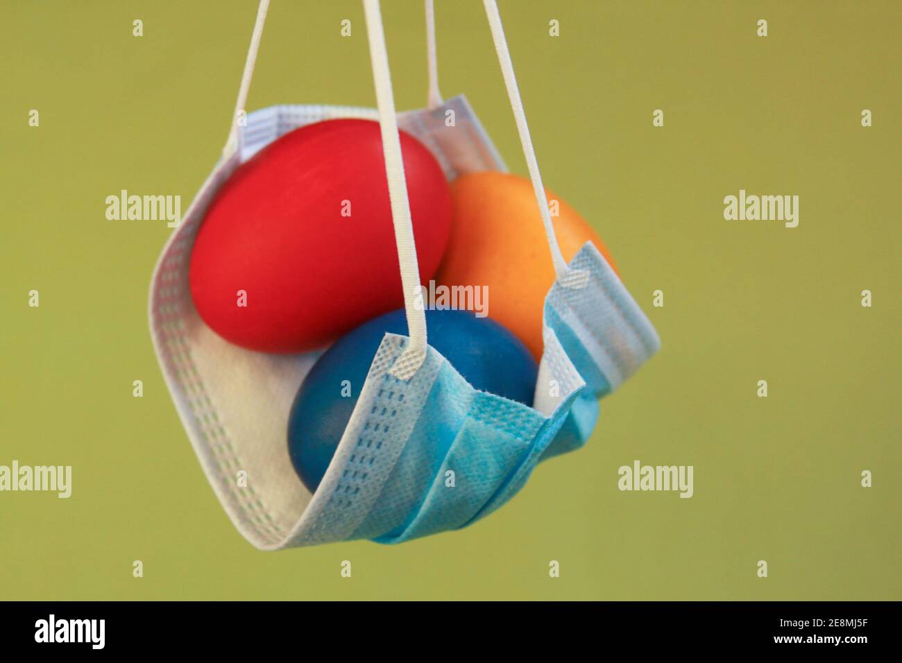 Huevos de Pascua coloreados aislados en máscara quirúrgica, un símbolo de la pandemia del coronavirus. La seguridad es lo primero en celebrar la Pascua 2020 covid 19 brote Foto de stock