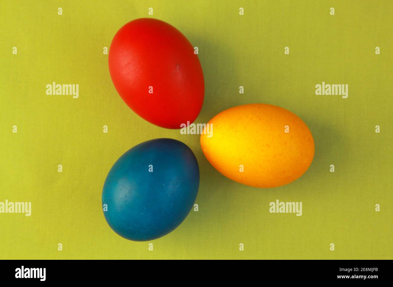 Redondo rojo, amarillo y azul huevos de Pascua de color sobre fondo verde vivo 2020 concepto. La pintura de huevos es una tradición cristiana durante las vacaciones de Pascua al Foto de stock