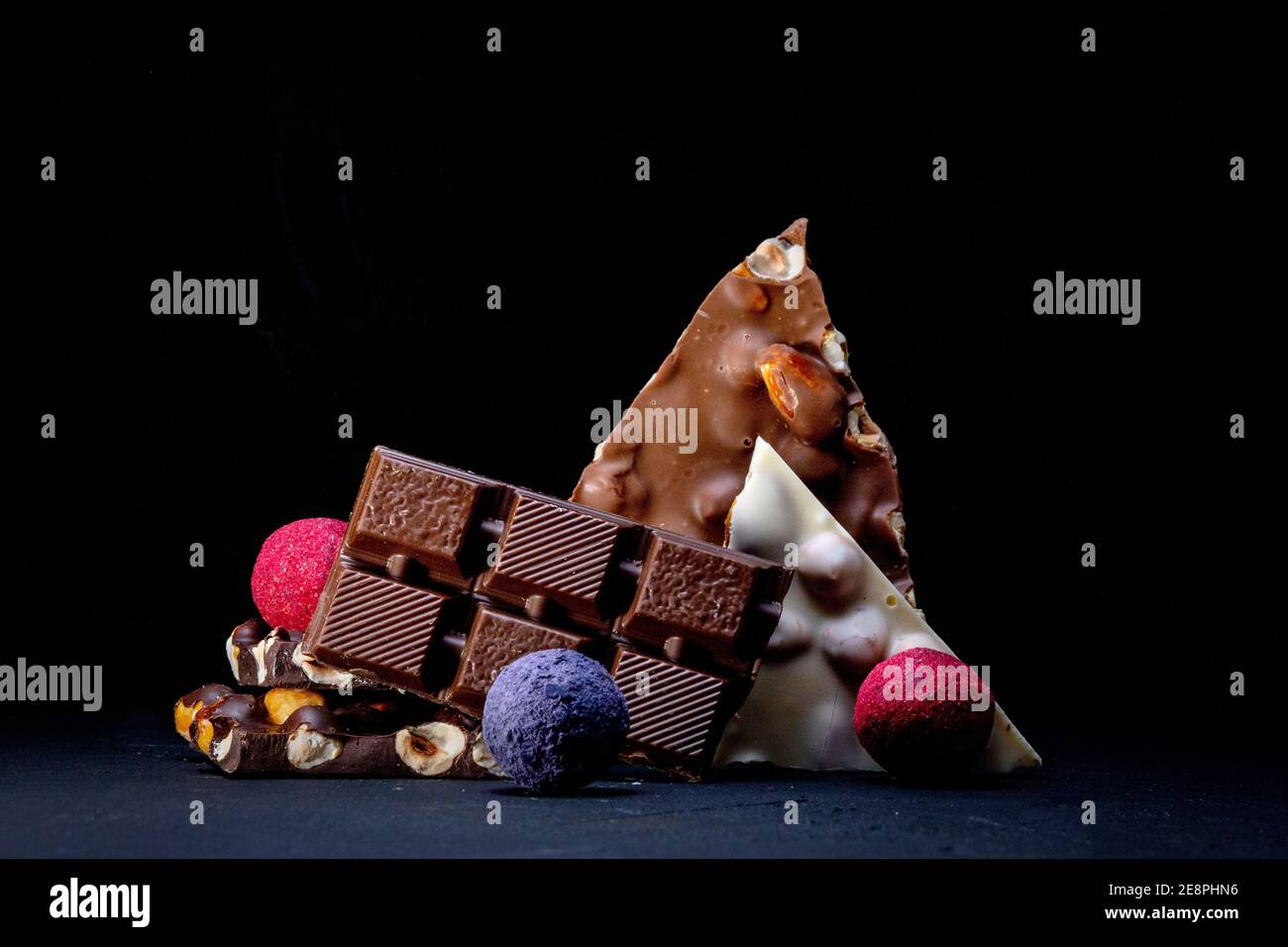 Trufa de chocolate con trozos de chocolate y polvo de cacao volador sobre un fondo oscuro. Foto de stock
