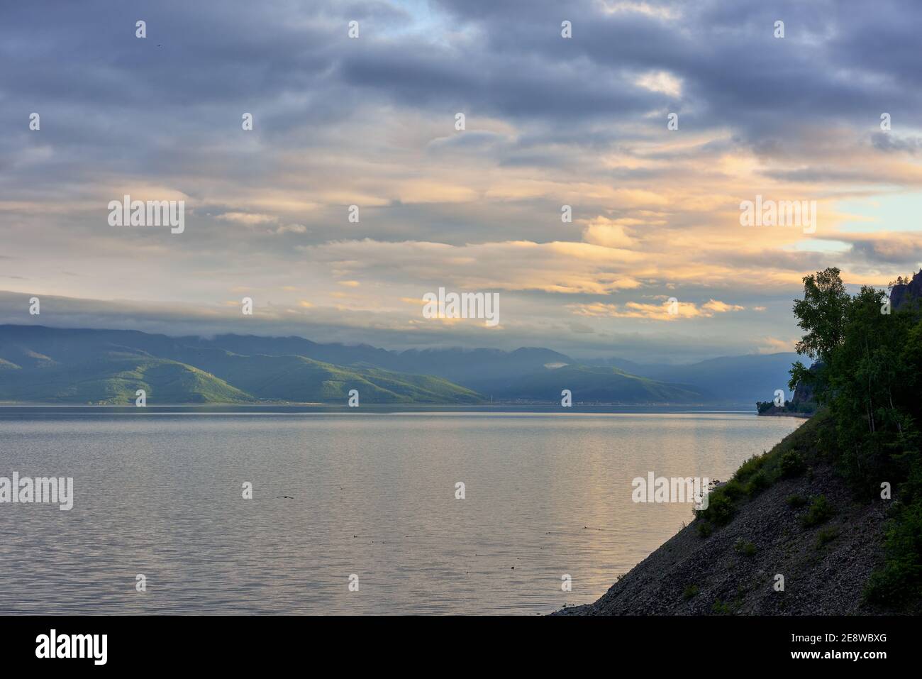 Noche Baikal. La luz del sol rompiendo a través de las nubes ilumina las colinas boscosas en Hamar-Daban. Junio. Región de Irkutsk Foto de stock