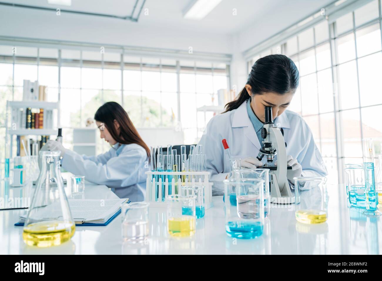 Primer plano del equipo de investigación científica asiática en protección equipo que utiliza el microscopio en el laboratorio para desarrollar la vacuna antivirus Foto de stock