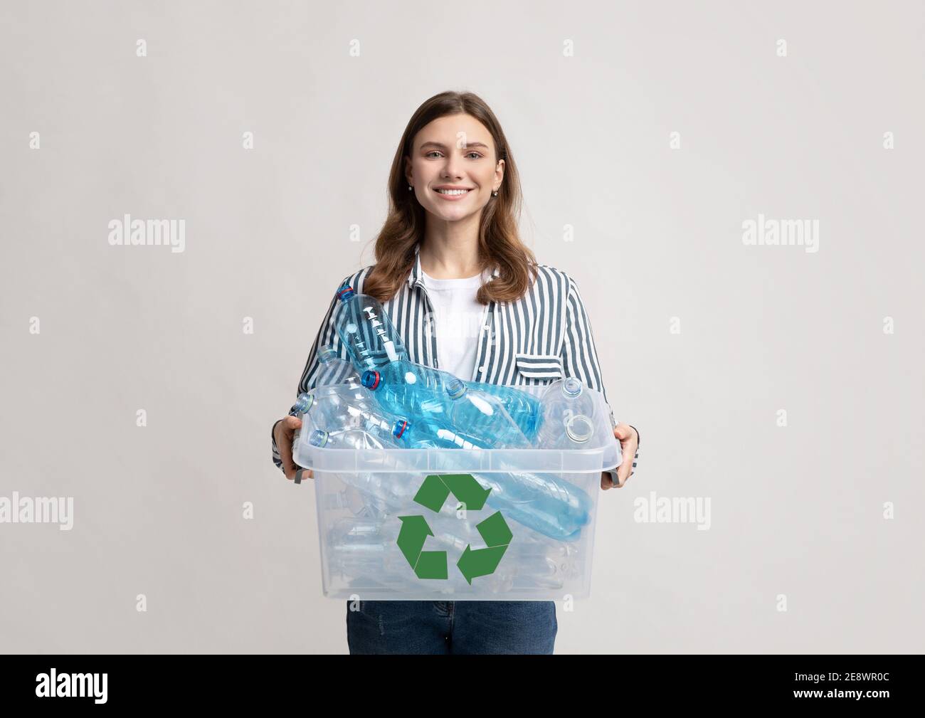 Reciclaje de plástico. Recipiente positivo de la celebración de la mujer del milenio con las botellas para el reciclaje Foto de stock