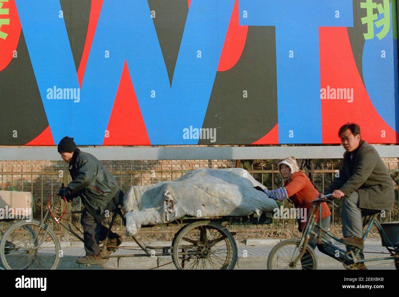 La gente pasa por una cartelera con China para unirse a la OMC en Beijing central, China. Noviembre de 2000. Foto de stock