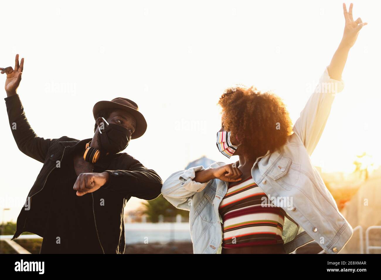 Amigos afro americanos con máscara protectora de cara haciendo nueva social distancia saludos golpeando codos Foto de stock
