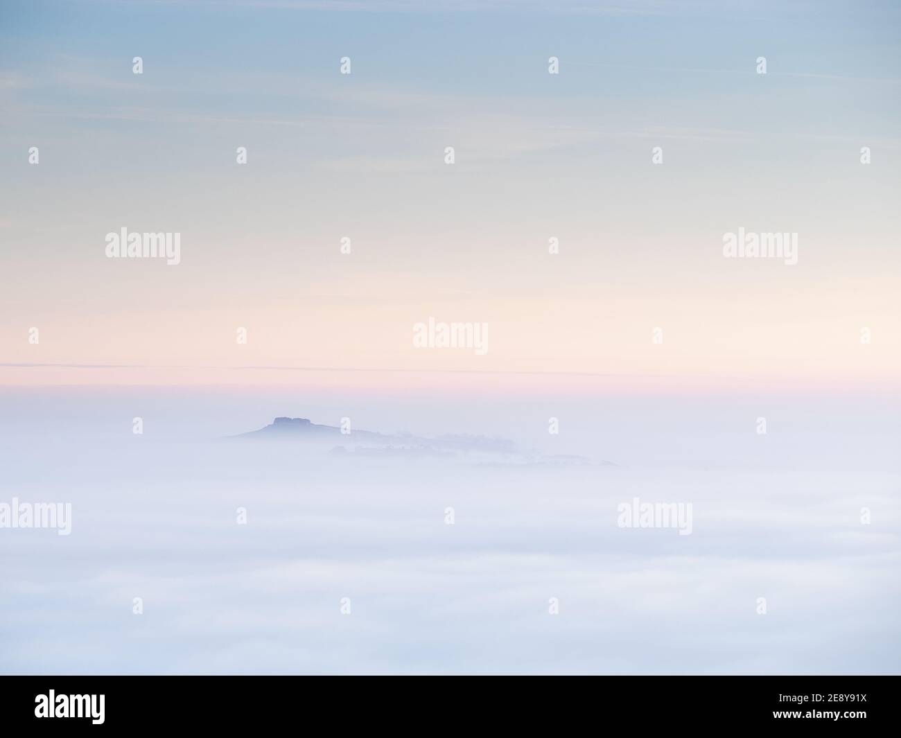 Almscliffe Crag se tamiza a través de un mar de niebla durante una inversión de la temperatura otoñal en el bajo Wharfedale, con el resto del paisaje oscurecido. Foto de stock