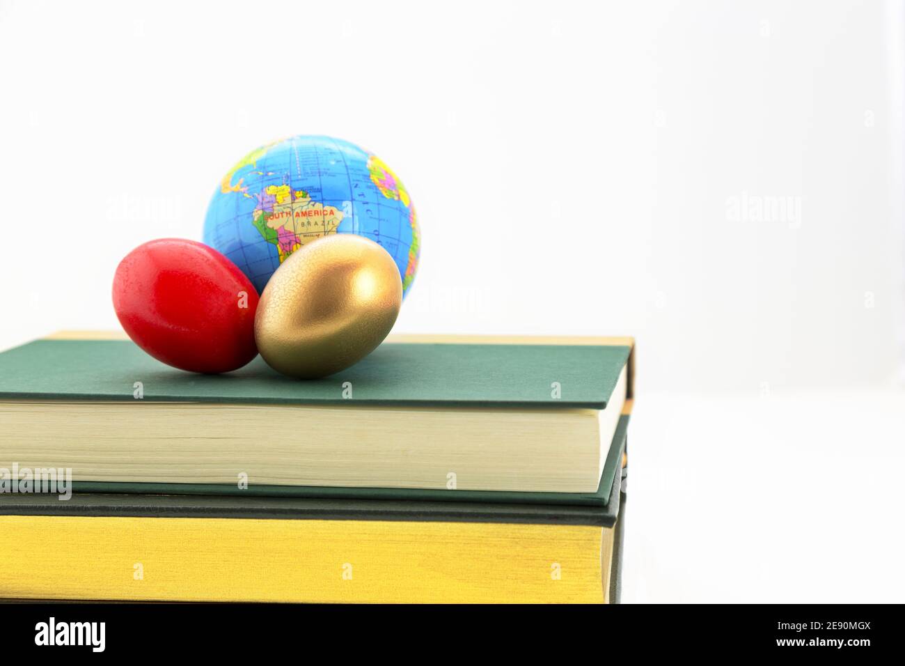 El huevo de oro, el huevo rojo y el globo en los libros son conceptos de los riesgos y beneficios empresariales de la industria mundial, retos y estrategias de éxito. Foto de stock