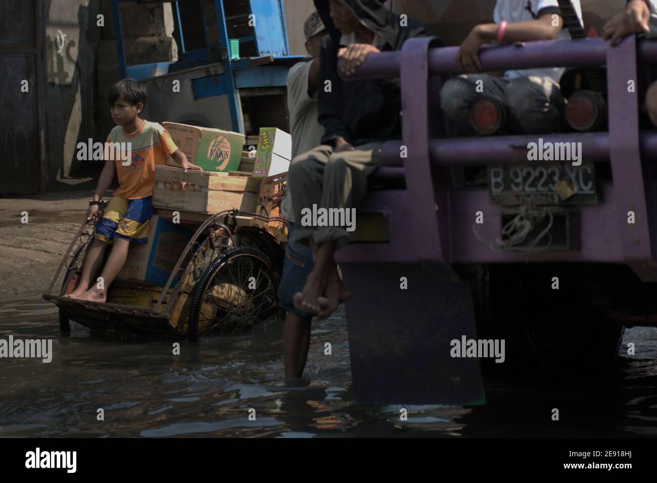 Tráfico en una calle costera inundada de agua de mar en Penjaringan, norte de Yakarta, Yakarta, Indonesia. Foto de stock