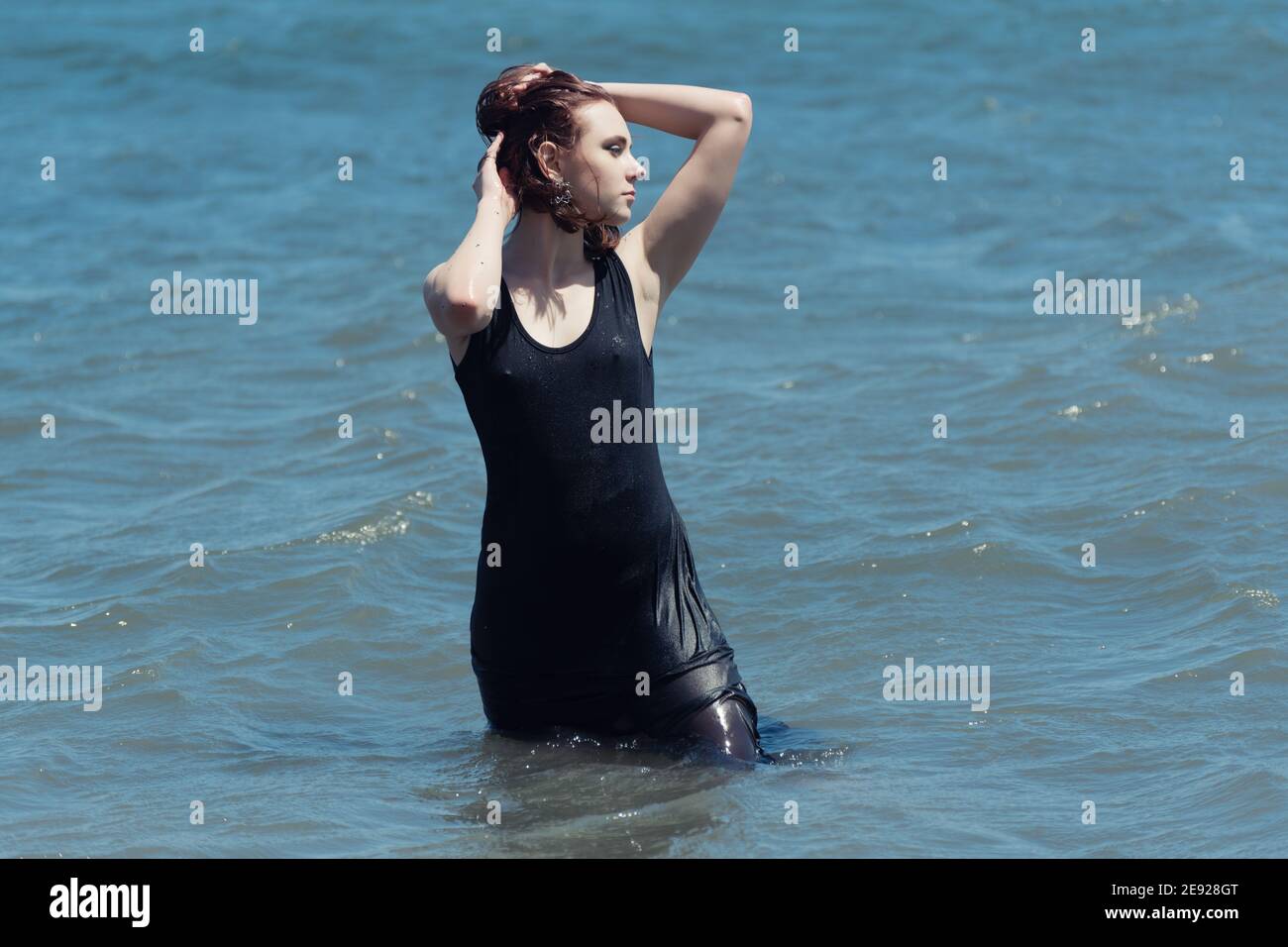 La joven con vestido negro disfruta del mar. Foto de stock