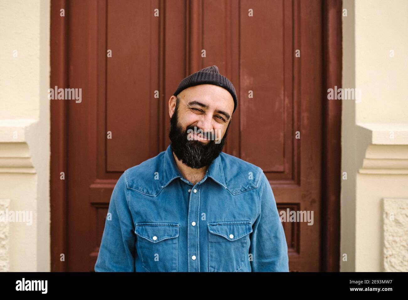Hombre sonriente de pie contra la puerta Foto de stock
