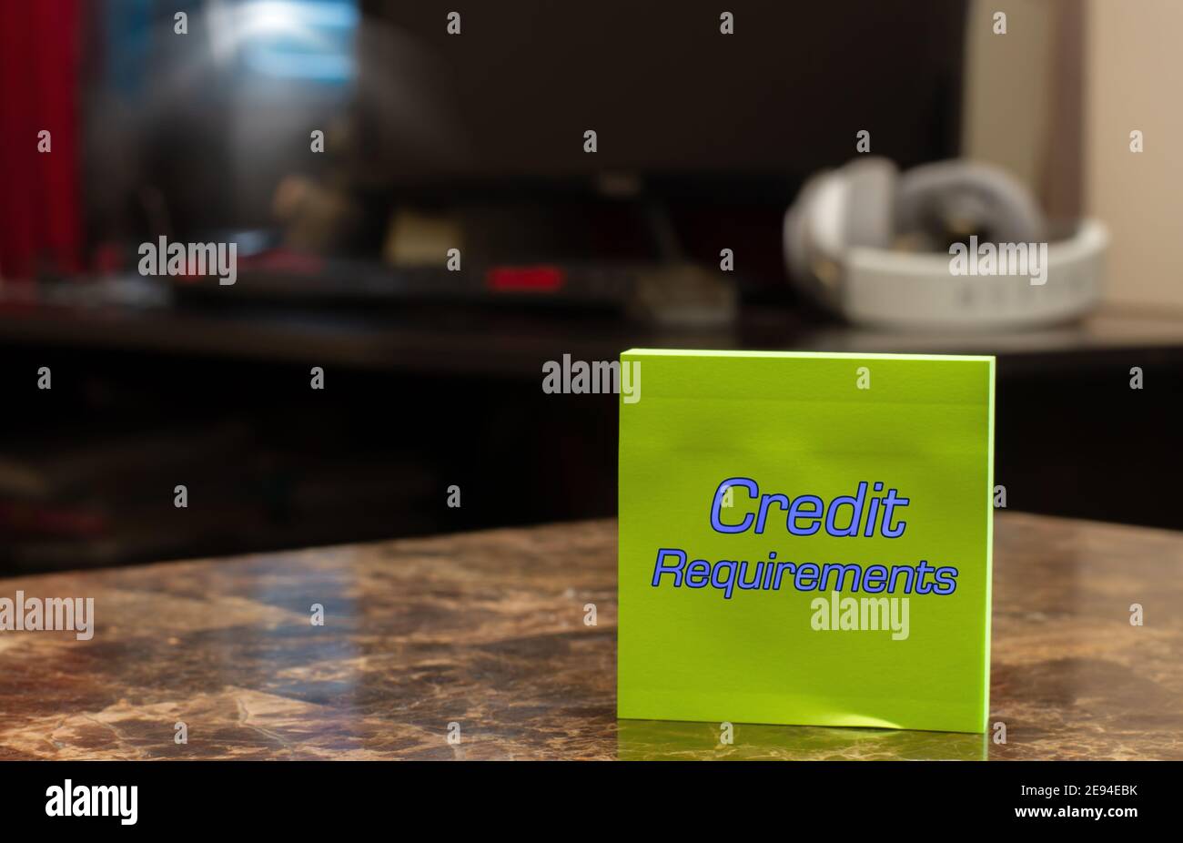 Requisitos de crédito. Texto en una etiqueta verde colocada sobre una mesa de mármol contra un fondo borroso de la oficina en casa. Foto de stock