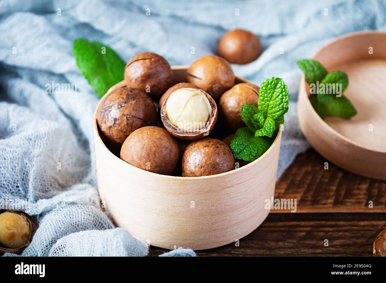 Nueces de macadamia en cáscara con hojas de menta y miel fondo de madera  Fotografía de stock - Alamy