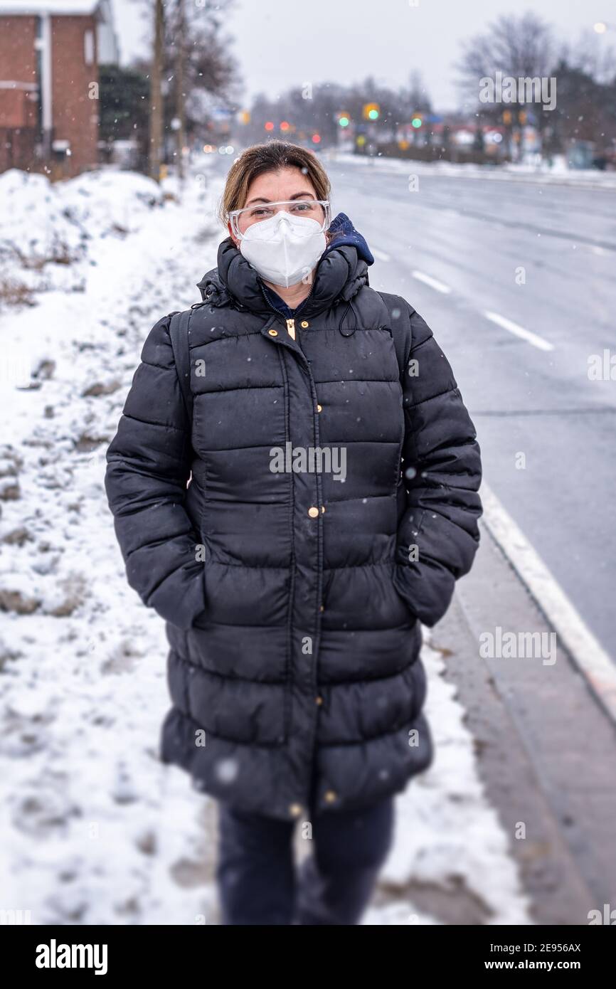 Covid-19 o Coronavirus, una mujer que lleva una máscara protectora en invierno, Canadá, 2021 Foto de stock